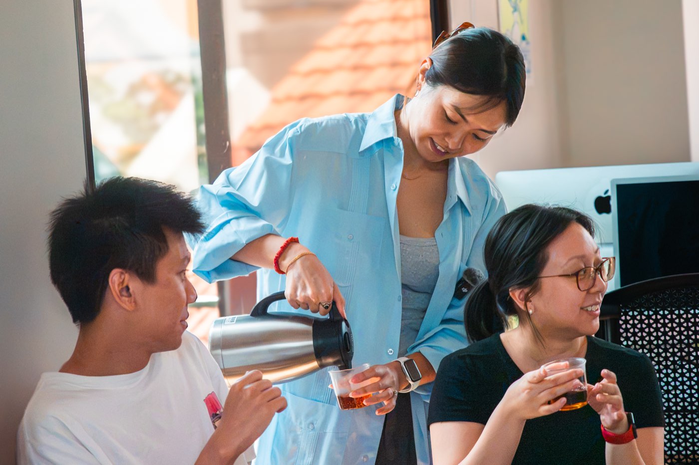 Keika pouring tea for two laughing guests at a Teasan tasting